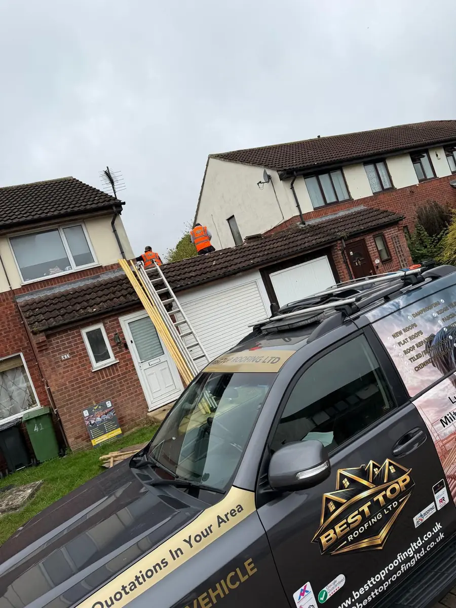 Best Top Roofing vehicle outside a job with roofers on the roof behind