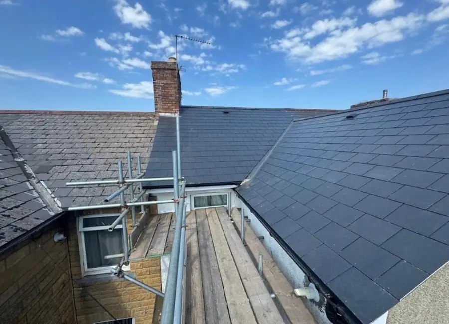 Dark slate-effect roof finished around a rear dormer, scaffold boards below