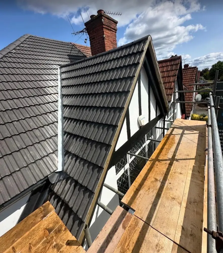 Dark interlocking tiles finished on a mock-Tudor house with a brick chimney
