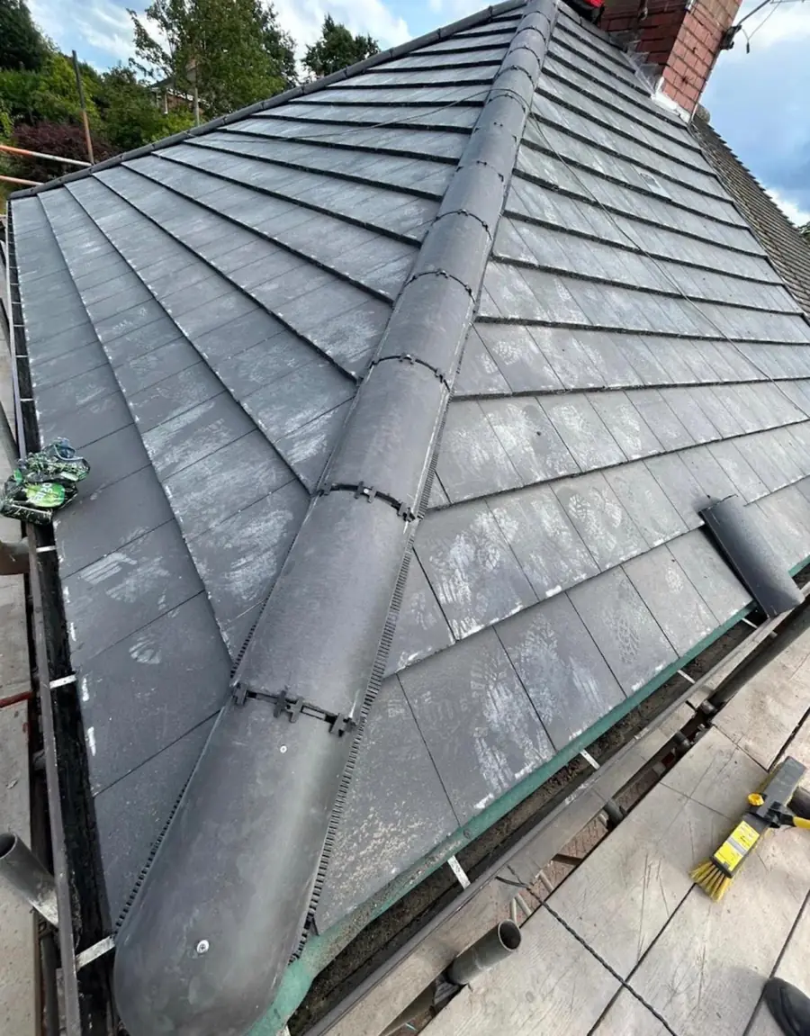 Grey slate-effect hip roof finished with a mechanically fixed dry hip and ridge