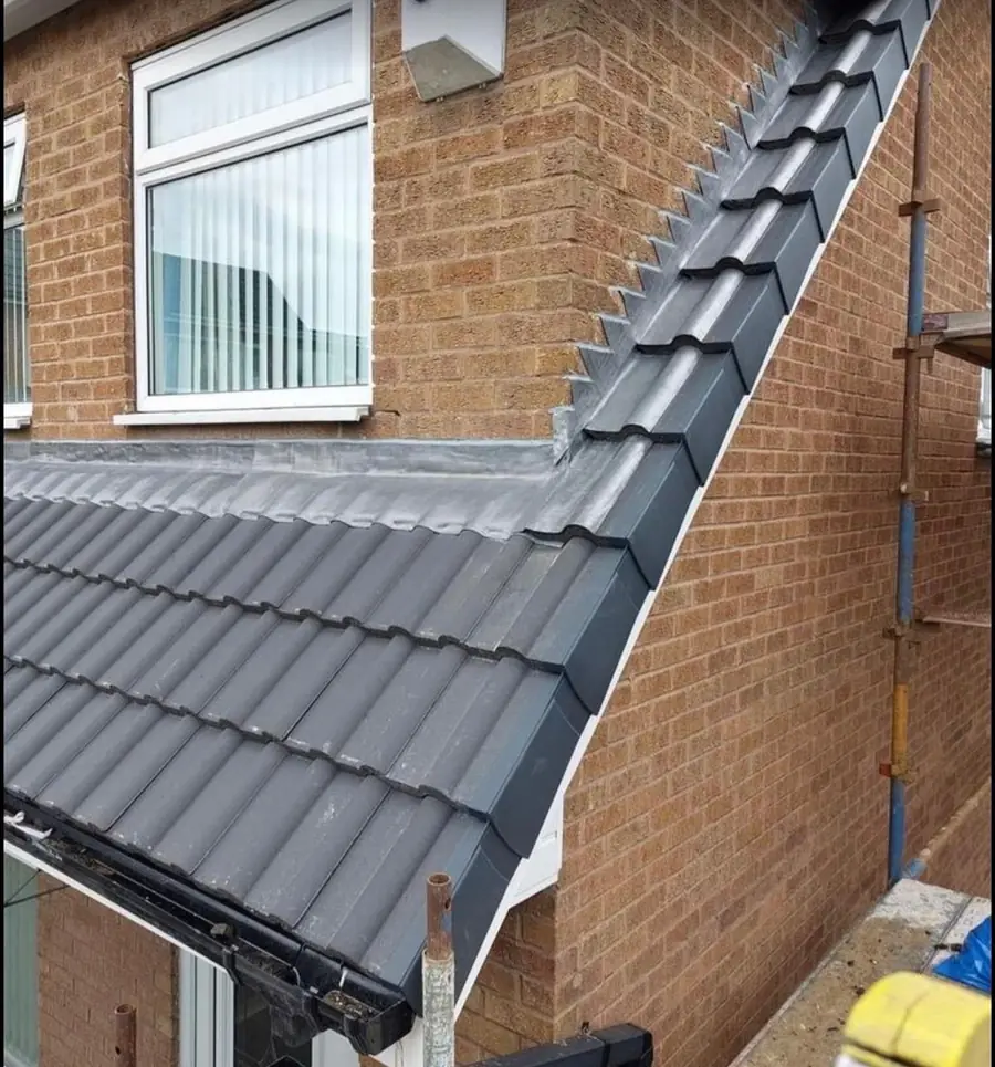 Grey interlocking tiles finished at the gable with a dry verge, brick wall beside