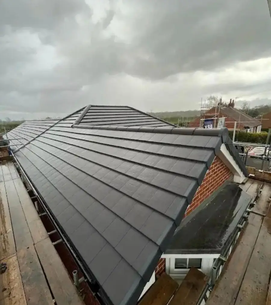 Finished re-roof in grey slate-effect tiles with a new dry verge, scaffold still up