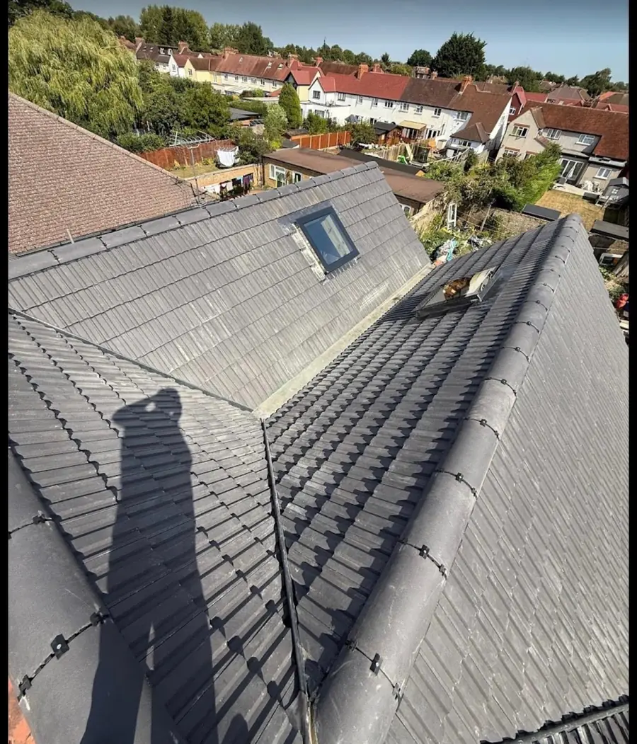 Grey tile roof with a valley and a roof window, finished, terraced street behind