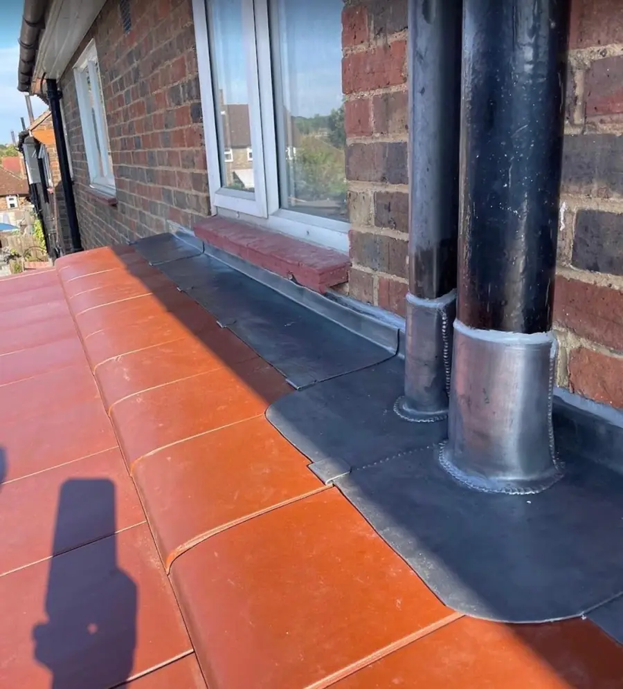 Lead flashing dressed around a soil pipe where a roof meets the wall