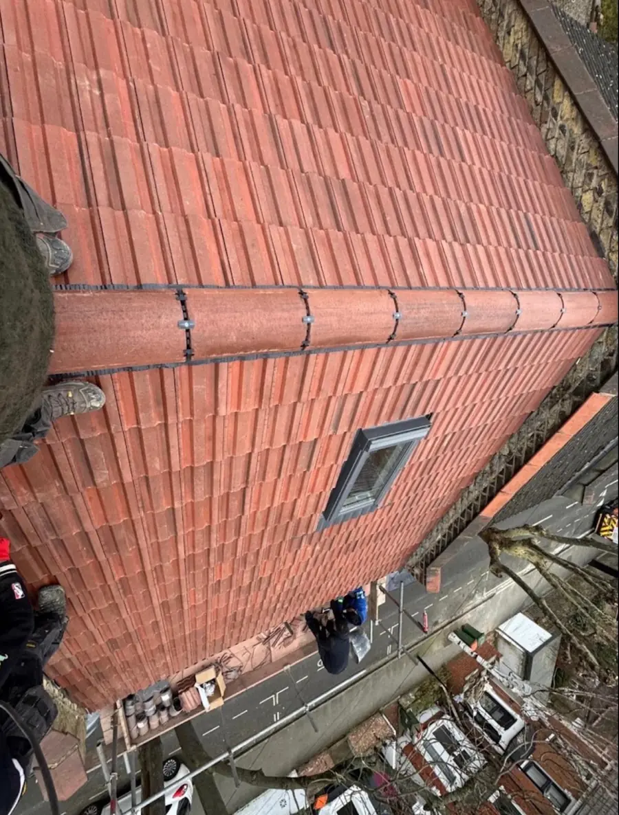 Red interlocking tile roof with a new roof window and dry ridge, seen from the scaffold