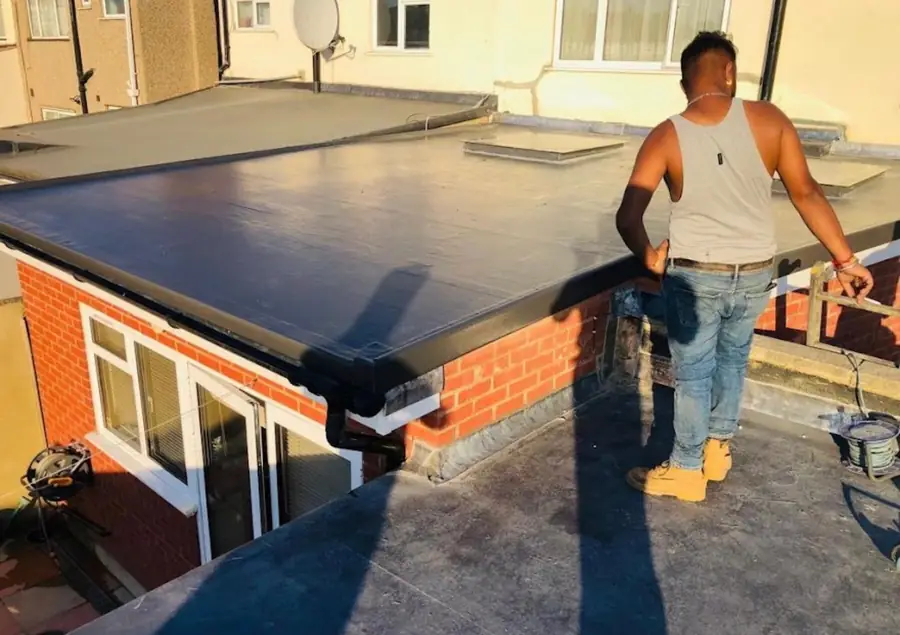 New rubber flat roof with black trims on a rear extension, roofer standing on it