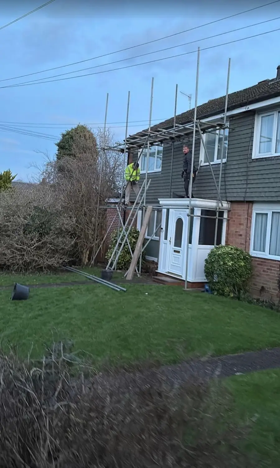 Semi-detached house with scaffold up and roofers at work on the roof