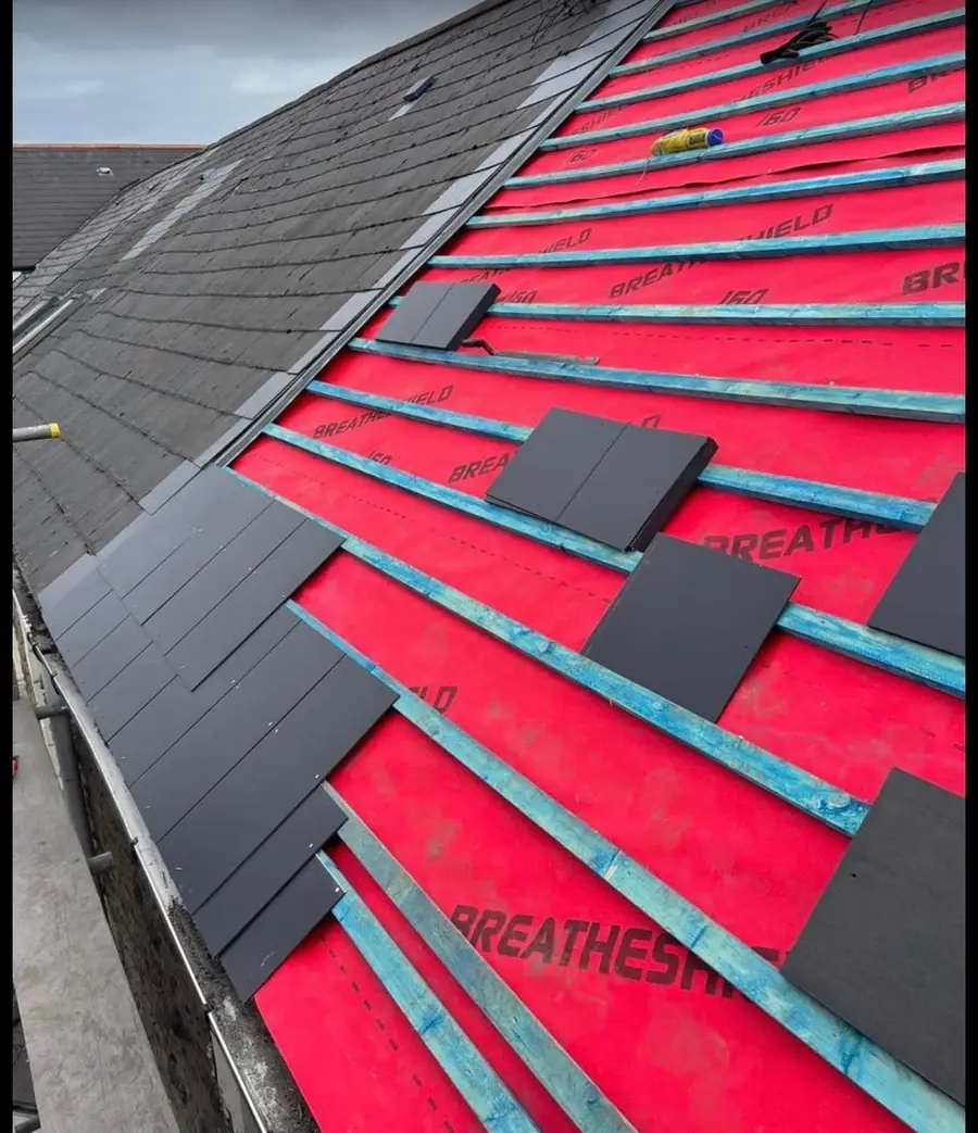 Close view of slate-effect tiles being fixed over red breathable membrane