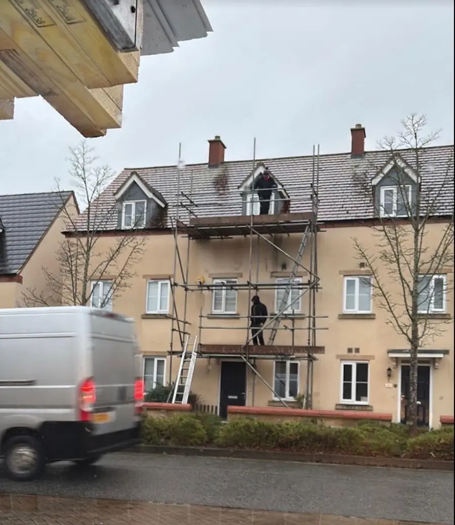 Three-storey townhouse terrace scaffolded for a re-roof, roofers on the lifts